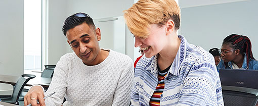 Students in a lecture room taking notes on laptops and pads of paper