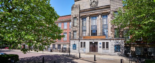 The entrance to the MA Wulfruna building, a set of double doors with plaques, pillar carvings and a stone coat of arms at the top of the building