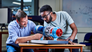 Model of jet engine with two people inspecting it.