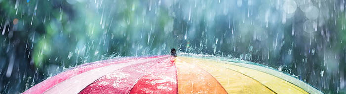 rainbow coloured umbrella with rain falling on it