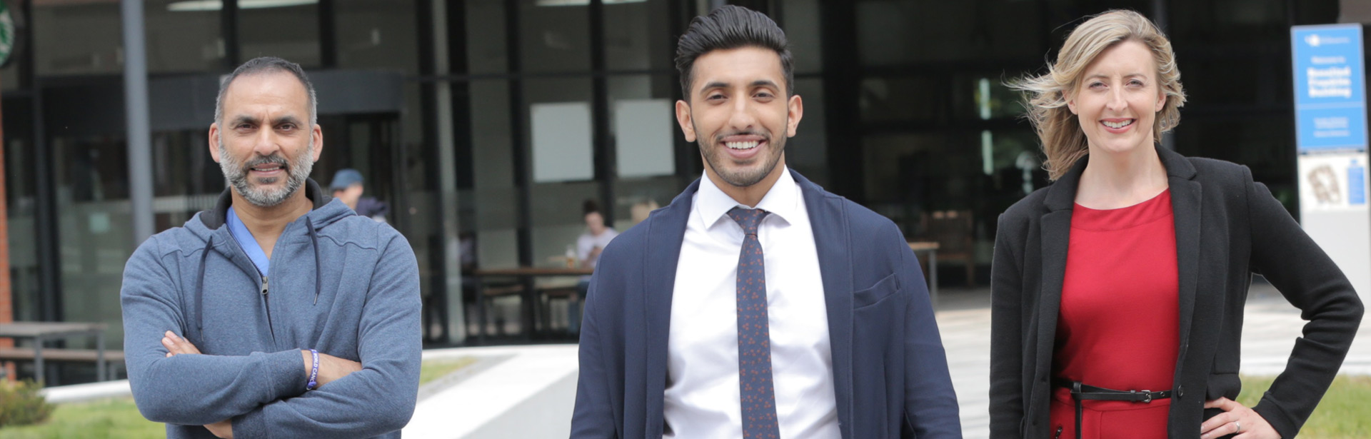 Three people stood in the courtyard to promote PG Week