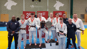 Athlete scholars in Judo, standing together wearing judogi in the sports hall and presenting their awards