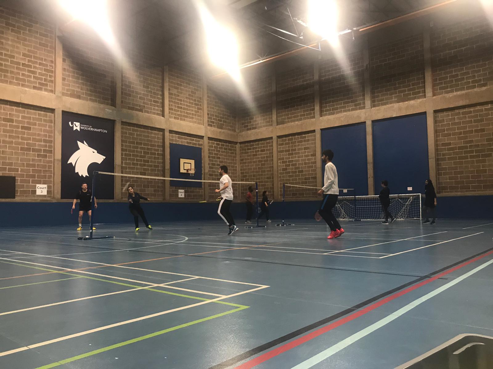 Students playing Badminton in the City Campus sports hall, wearing uniforms with University of Wolverhampton branding