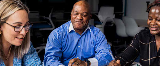 Three Postgraduate students, one male and two female sat around a table