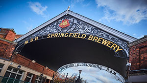 Arch at Springfield Campus, a metalwork crest hanging above signage reading M and B Springfield Brewery